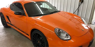 Orange Porsche Cayman, front three-quarter view